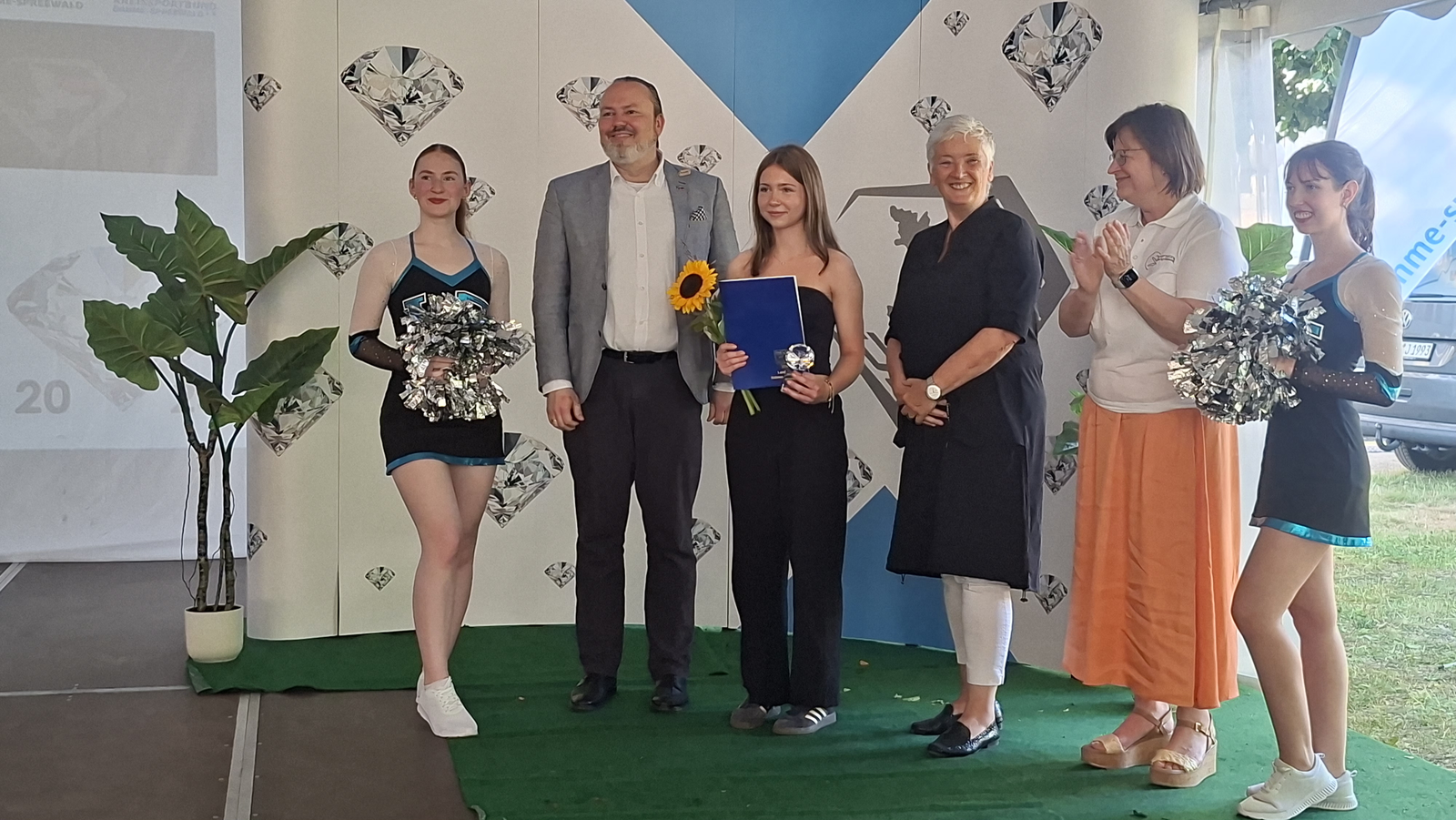 Vivien Meyer mit Urkunde, Pokal und Sonnenblume auf der Bühne